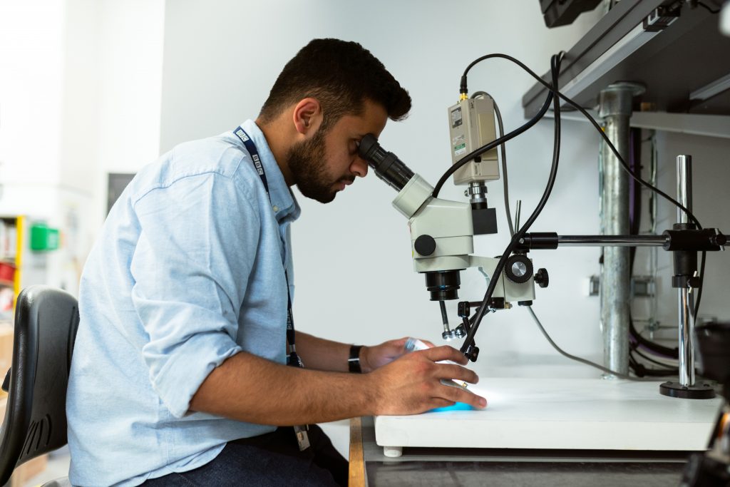 Male broadcast engineer using a microscope